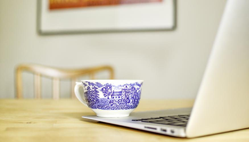 Kuva kannettavasta tietokoneesta, jonka päällä on kahvikuppi